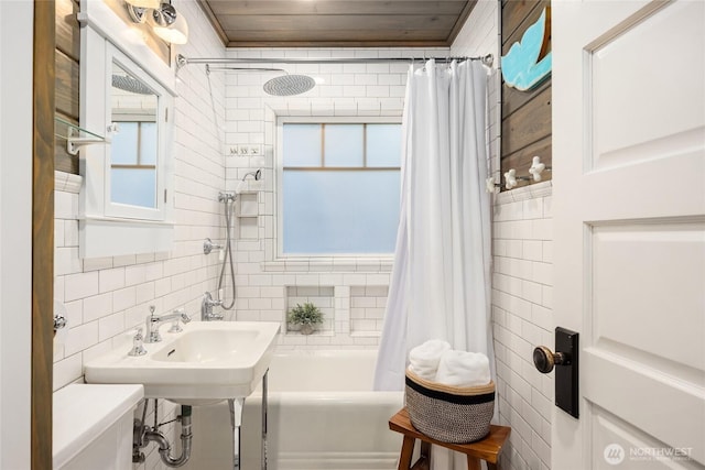 bathroom with toilet, shower / bath combination with curtain, tile walls, and a healthy amount of sunlight