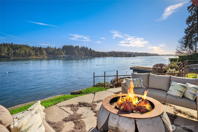 water view featuring a dock, a fire pit, and a forest view