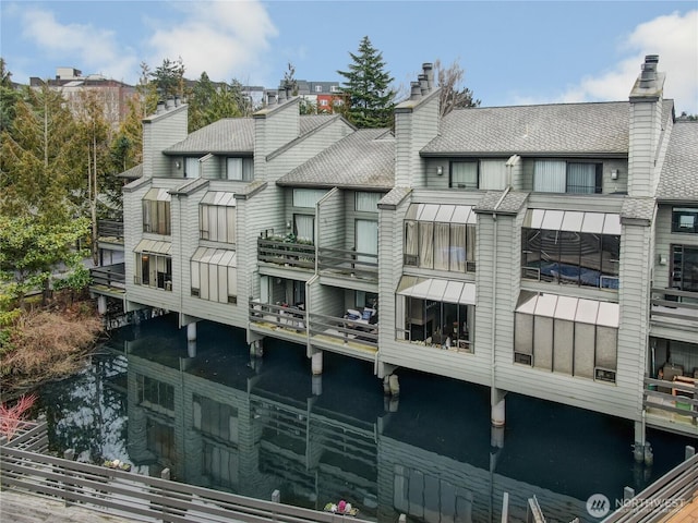 back of house featuring a water view and a chimney