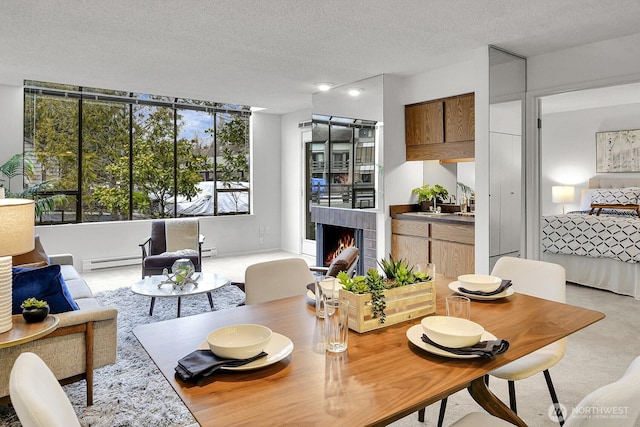 dining room featuring a lit fireplace, baseboard heating, and a textured ceiling