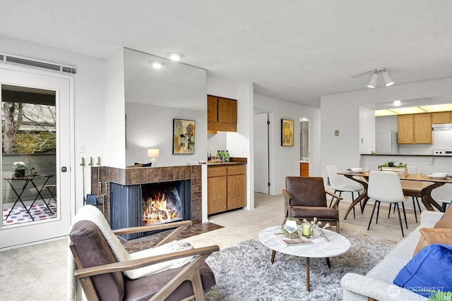 living room featuring light carpet and a fireplace with flush hearth