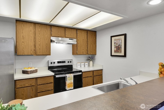 kitchen with brown cabinetry, electric stove, freestanding refrigerator, under cabinet range hood, and a sink