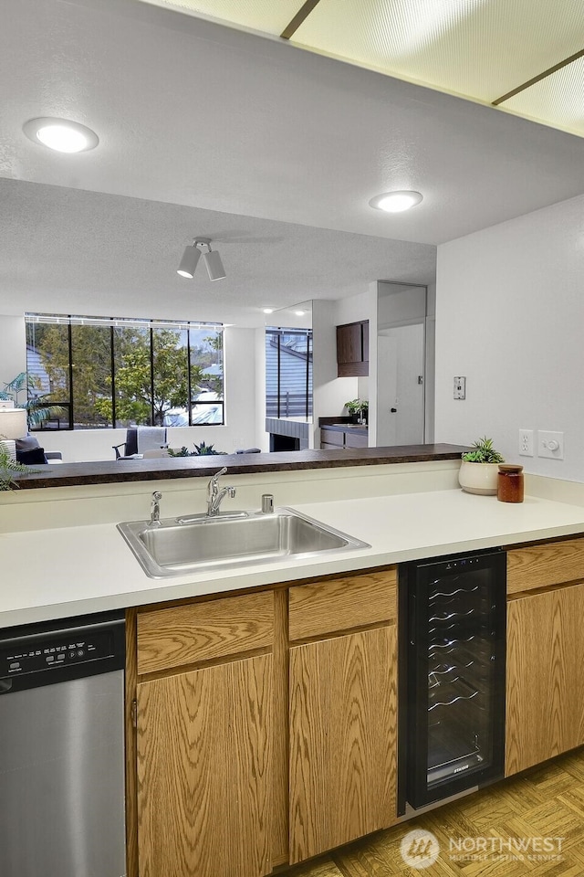 kitchen featuring wine cooler, light countertops, a sink, and stainless steel dishwasher