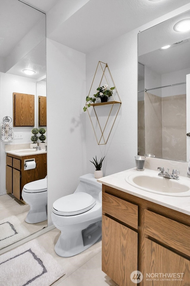 bathroom with toilet, tile patterned flooring, walk in shower, and vanity