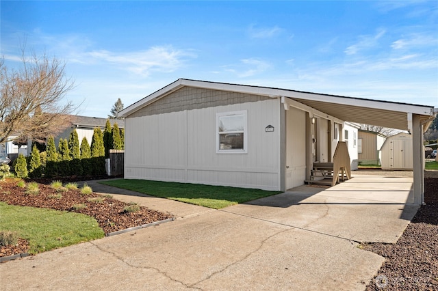 view of side of property featuring a carport, concrete driveway, an outdoor structure, and a storage unit