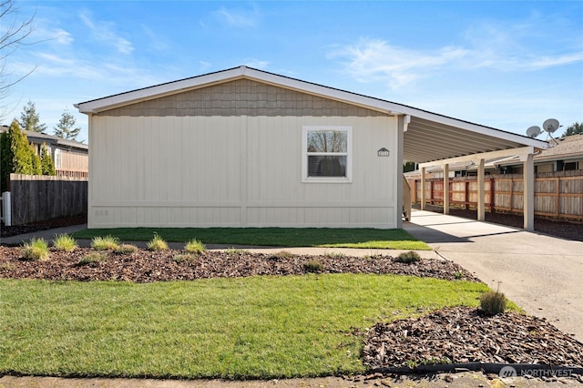 view of side of property with driveway, fence, an attached carport, and a yard