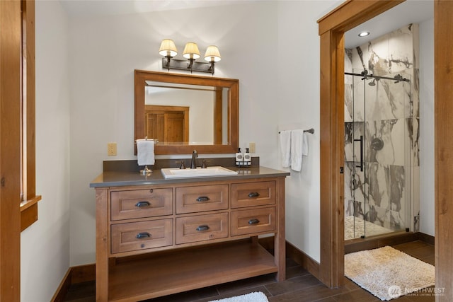 full bathroom with a marble finish shower, baseboards, and vanity