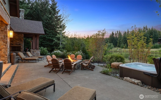 view of patio / terrace featuring a hot tub, a fireplace, and a fire pit