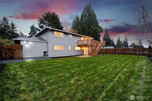 back of house at dusk with a deck, fence, a lawn, and stairs