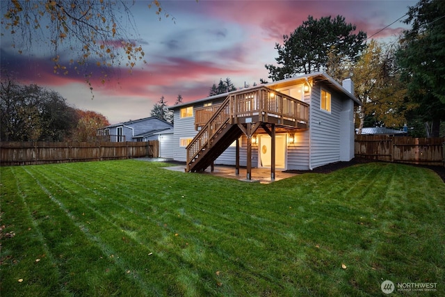 rear view of house with a fenced backyard, a lawn, a wooden deck, and stairs