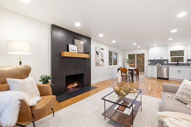 living room featuring recessed lighting, a fireplace, light wood-style flooring, and baseboards