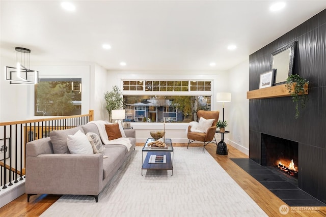 living room featuring recessed lighting, a fireplace, and wood finished floors