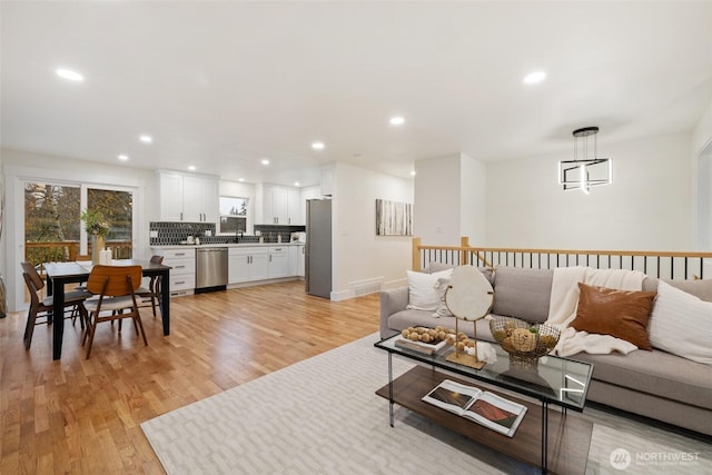 living room with baseboards, light wood finished floors, and recessed lighting