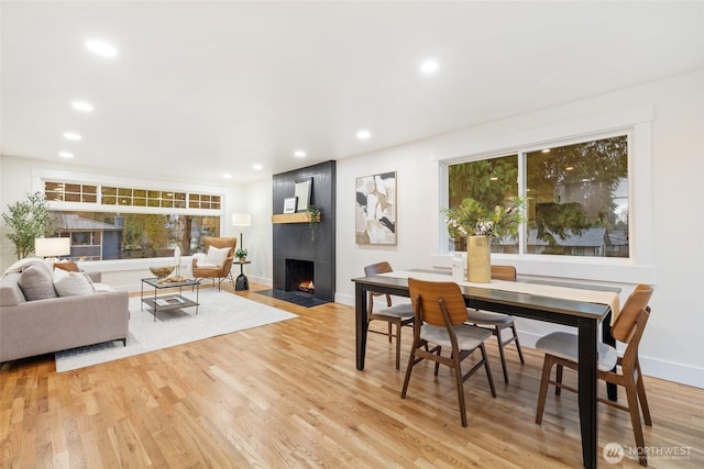 dining room with a large fireplace, light wood-style flooring, baseboards, and recessed lighting