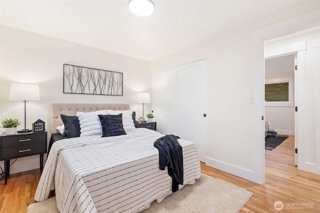 bedroom featuring a closet, baseboards, and light wood finished floors