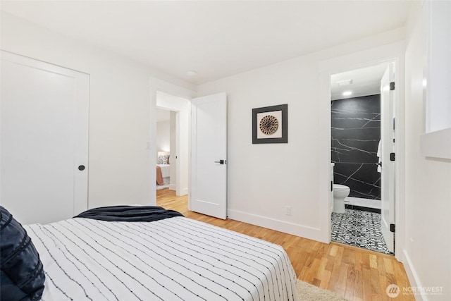 bedroom featuring baseboards, a closet, ensuite bathroom, and light wood-style floors