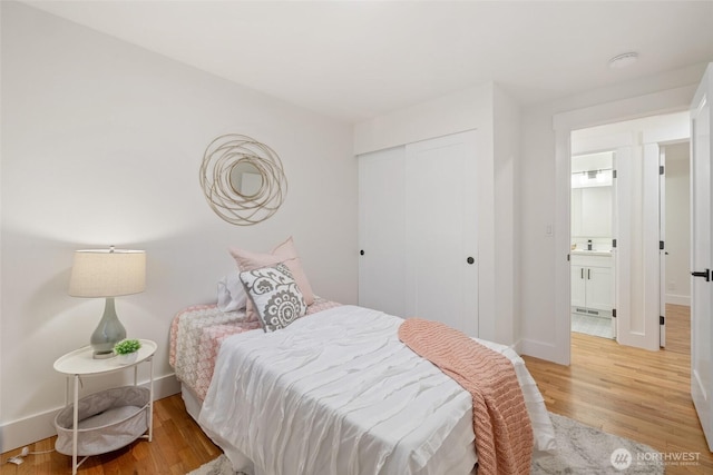 bedroom featuring a sink, light wood finished floors, baseboards, and a closet