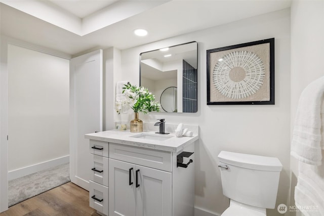 bathroom with vanity, wood finished floors, toilet, and baseboards