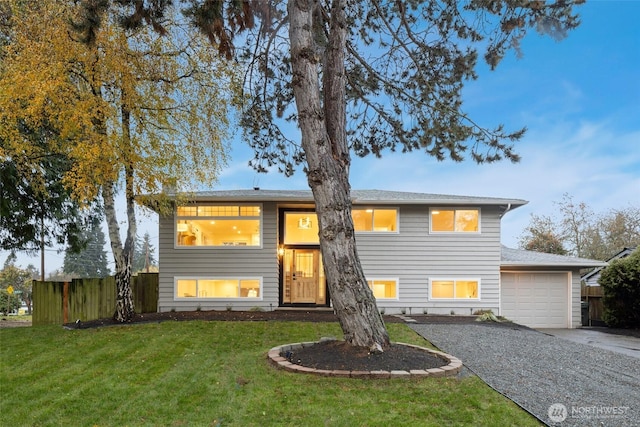 split foyer home with a front yard, fence, driveway, and an attached garage