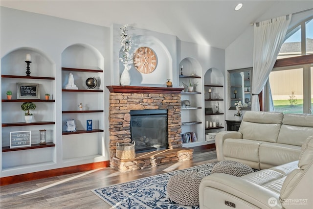 living area with a fireplace, built in features, vaulted ceiling, and wood finished floors