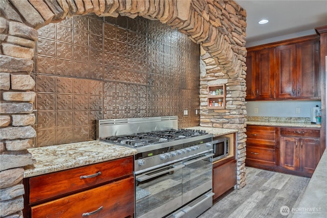 kitchen with light stone countertops, light wood finished floors, stainless steel appliances, and recessed lighting