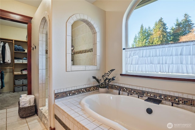 full bath with a garden tub, a spacious closet, and tile patterned floors