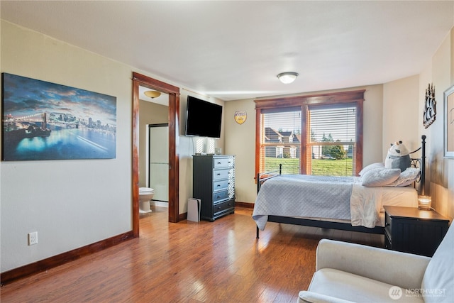 bedroom with baseboards, wood finished floors, and ensuite bathroom