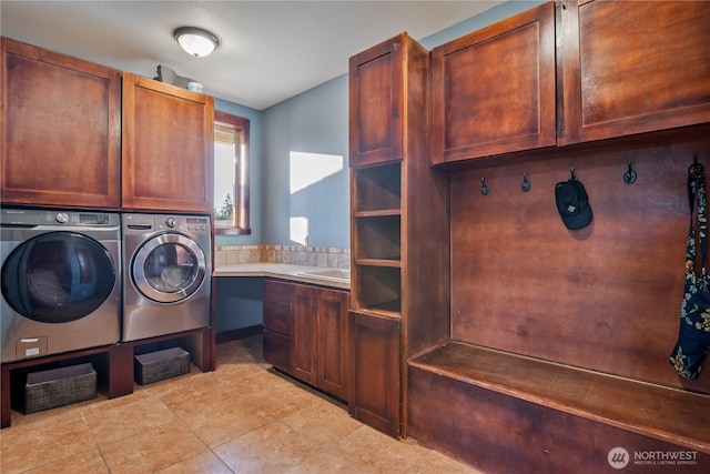 clothes washing area with cabinet space, light tile patterned floors, a sink, and washing machine and clothes dryer