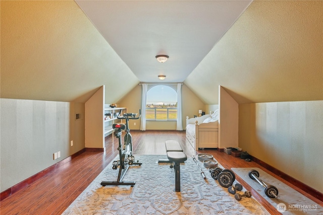 workout room with lofted ceiling, wood finished floors, and baseboards