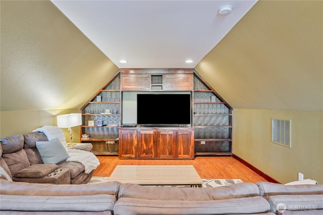 living room with lofted ceiling, light wood finished floors, visible vents, and baseboards