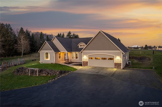 craftsman-style house featuring a garage, central AC, a yard, stone siding, and driveway