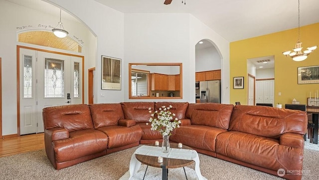 living area with visible vents, arched walkways, light wood-style floors, and a chandelier