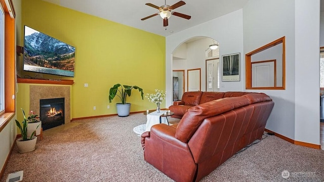 carpeted living area with visible vents, ceiling fan, baseboards, and a fireplace with flush hearth