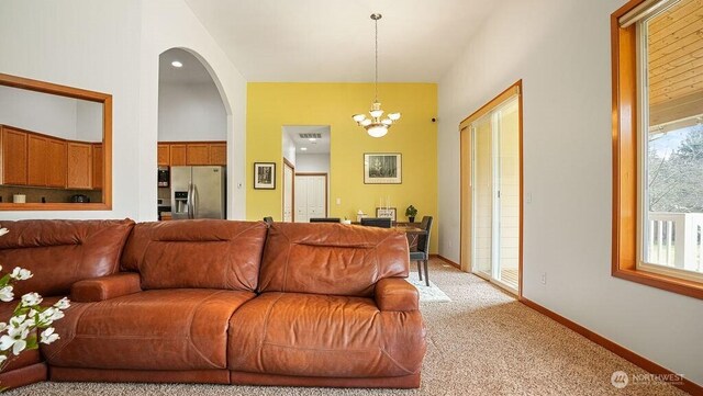 living room with visible vents, light carpet, arched walkways, baseboards, and a chandelier