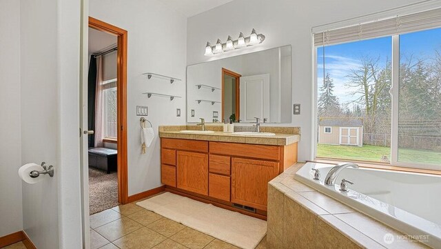 bathroom with a sink, double vanity, a wealth of natural light, and tile patterned floors