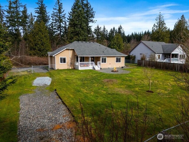 rear view of property featuring fence, an outdoor fire pit, covered porch, a yard, and a gate