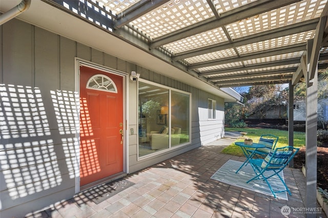 entrance to property featuring board and batten siding, a patio area, and a pergola