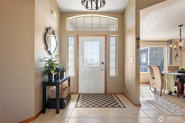 entrance foyer featuring an inviting chandelier, plenty of natural light, light tile patterned floors, and baseboards