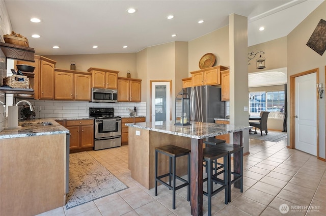 kitchen featuring tasteful backsplash, a kitchen island, appliances with stainless steel finishes, and light tile patterned flooring