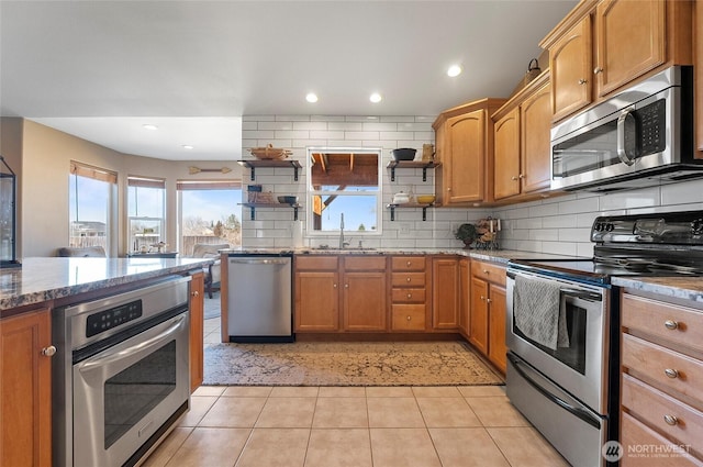 kitchen featuring stone counters, stainless steel appliances, a sink, decorative backsplash, and open shelves