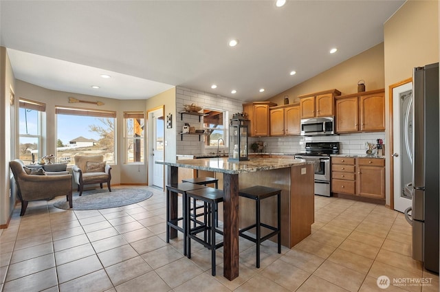 kitchen featuring light tile patterned floors, stainless steel appliances, tasteful backsplash, and light stone counters