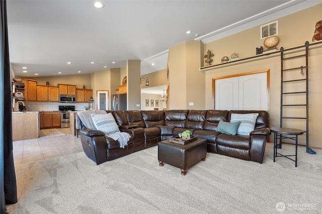 living area with light tile patterned floors, lofted ceiling, a barn door, light carpet, and visible vents