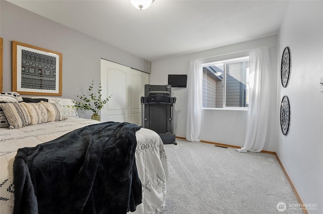 bedroom with a closet, light colored carpet, and baseboards