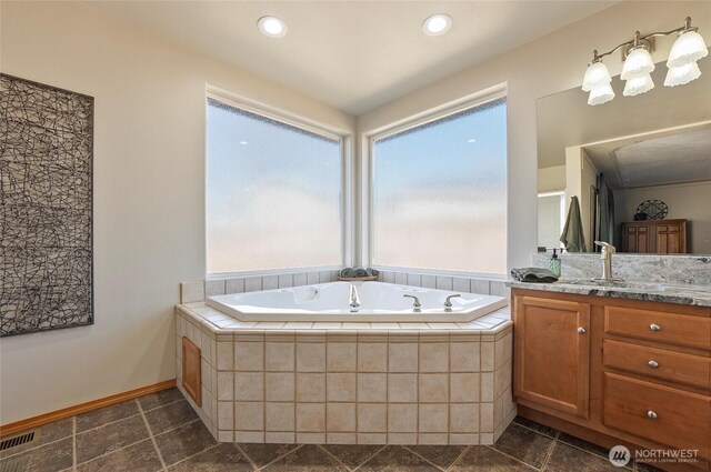 full bath featuring stone tile floors, vanity, baseboards, visible vents, and a bath