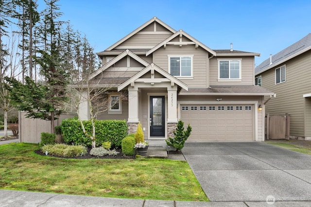 craftsman house featuring fence, driveway, an attached garage, a front lawn, and stone siding