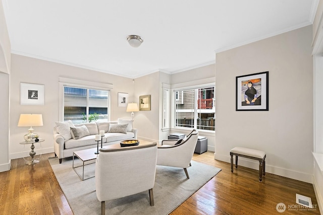 living area featuring visible vents, crown molding, baseboards, and wood finished floors