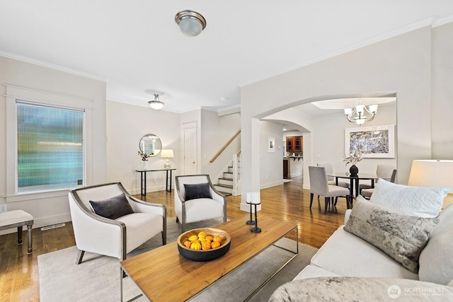 living area featuring arched walkways, ornamental molding, stairway, and wood finished floors