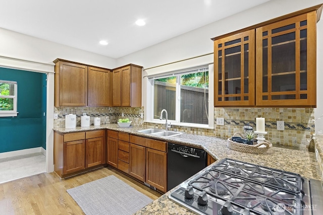 kitchen featuring light wood-style floors, a wealth of natural light, black dishwasher, and a sink