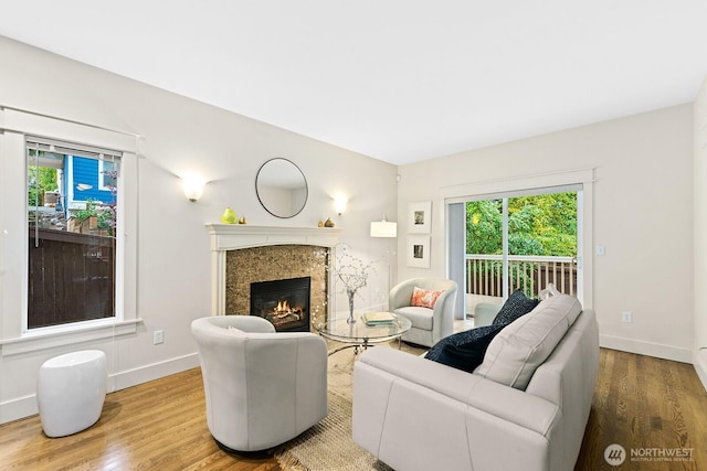 living area featuring a high end fireplace, baseboards, and wood finished floors