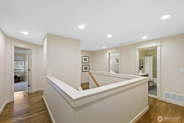 hallway featuring visible vents, dark wood-style floors, an upstairs landing, and recessed lighting